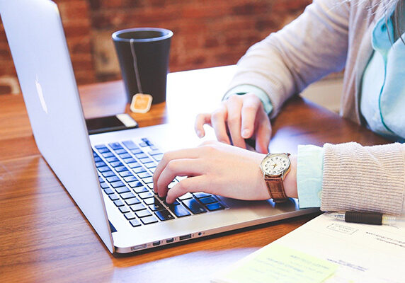 person searching on laptop with coffee cup